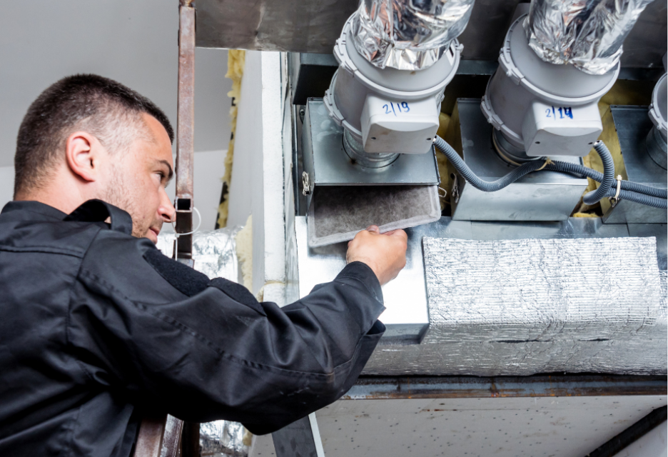 a technician is installing a filter into a heavy duty duct system.  there are two ducts leading into a large HVAC unit.